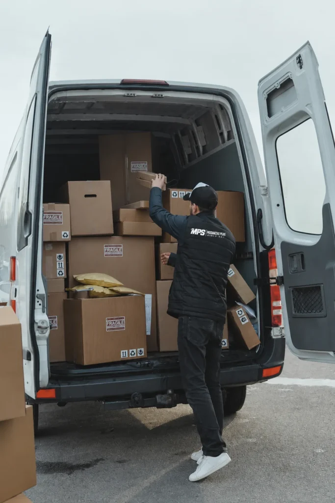 Operario de Mudanzas Plus Siglo XXI cargando cajas marcadas como frágiles en una furgoneta